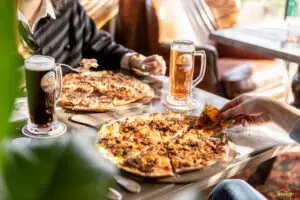Photographe entreprise Clermont-Ferrand : Couple à table au restaurant avec deux pizza et deux bière - Mise en scène de produits artisanaux – photographie de produits en Auvergne