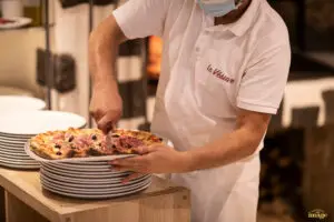 Employé de restaurant coupant une pizza - Image produit soignée – photographe professionnelle en Auvergne