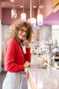 Femme avec des lunettes et les cheveux bouclés, acoudé à un bar - Séance photo professionnelle en entreprise - photographe professionnel Clermont-Ferrand – Puy-de-Dôme